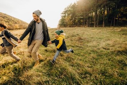 dad running in field with two boys